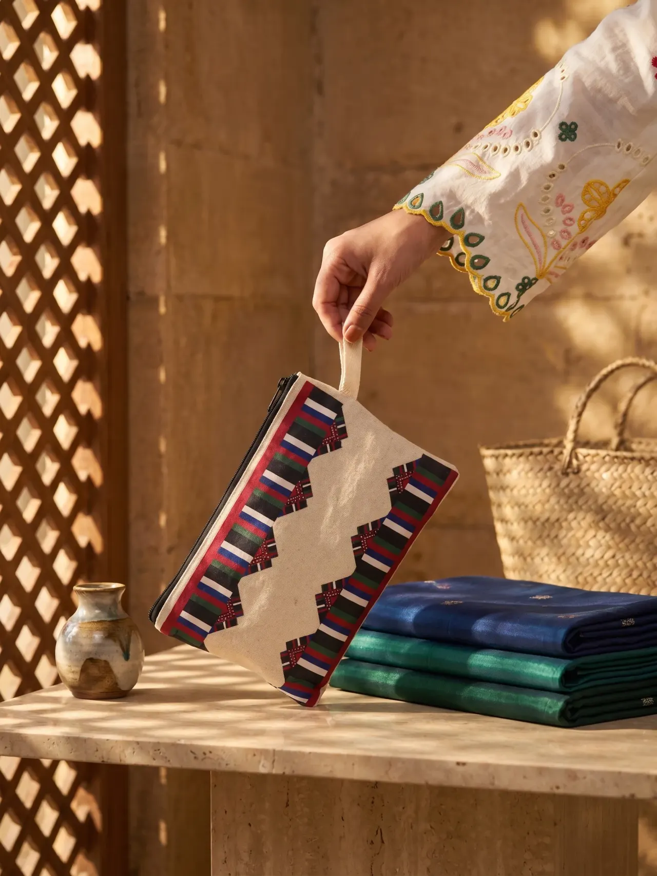 A canvas pouch with a red, blue, green and black chevron stripe pattern and a fabric loop handle